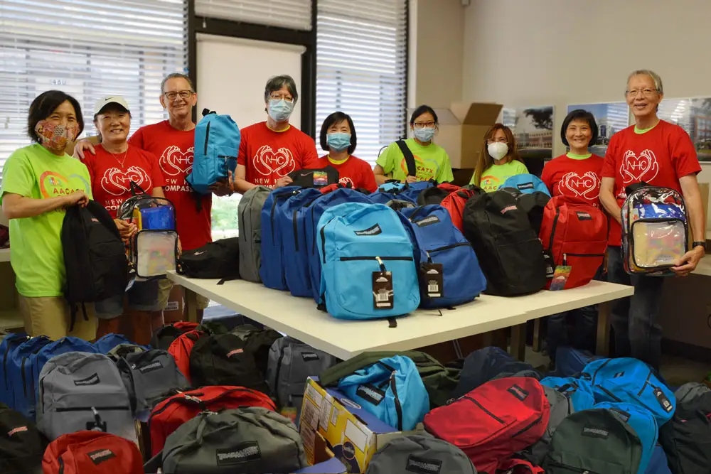 Group of volunteers preparing backpacks filled with supplies.