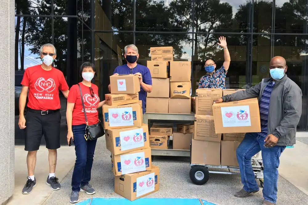 Volunteers with masks organising labelled boxes outdoors.