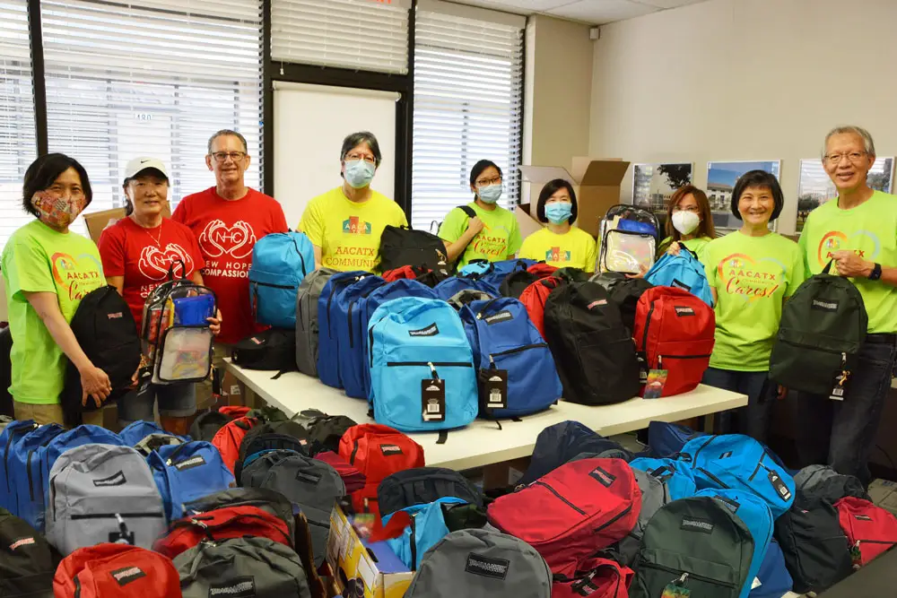 Volunteers preparing backpacks filled with school supplies.
