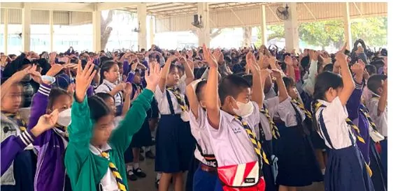 Schoolchildren in Thailand raising their hands at a Christmas outreach assembly.